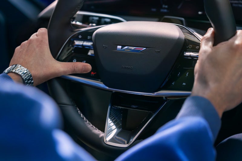 Close-up of a Man About to Press the V-Button on the 2026 OPTIQ-V Steering Wheel | Lavery Cadillac in Alliance OH