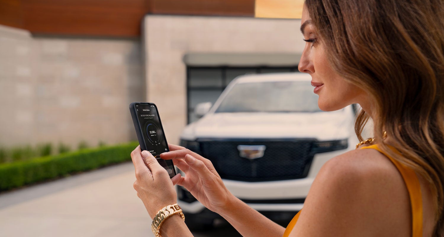 lady checking her mobile with a Cadillac vehicle background | Lavery Cadillac in Alliance OH